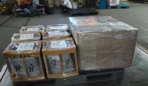 Palet kayu berisi barang elektronik, terbungkus plastik stretch wrap untuk keamanan selama pengiriman.